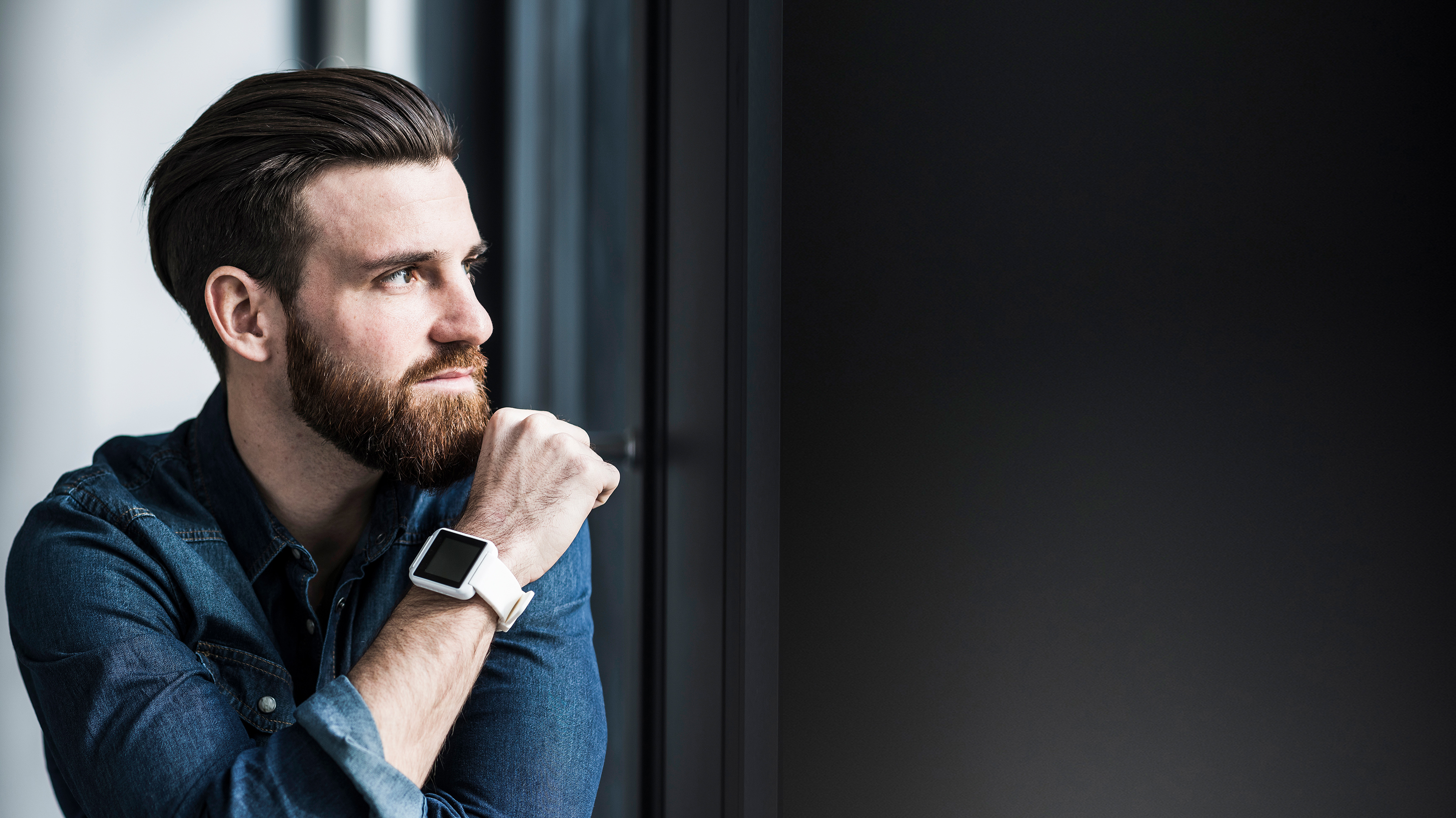 Zeitwirtschaft Mann mit Bart vor dunklem Hintergrund